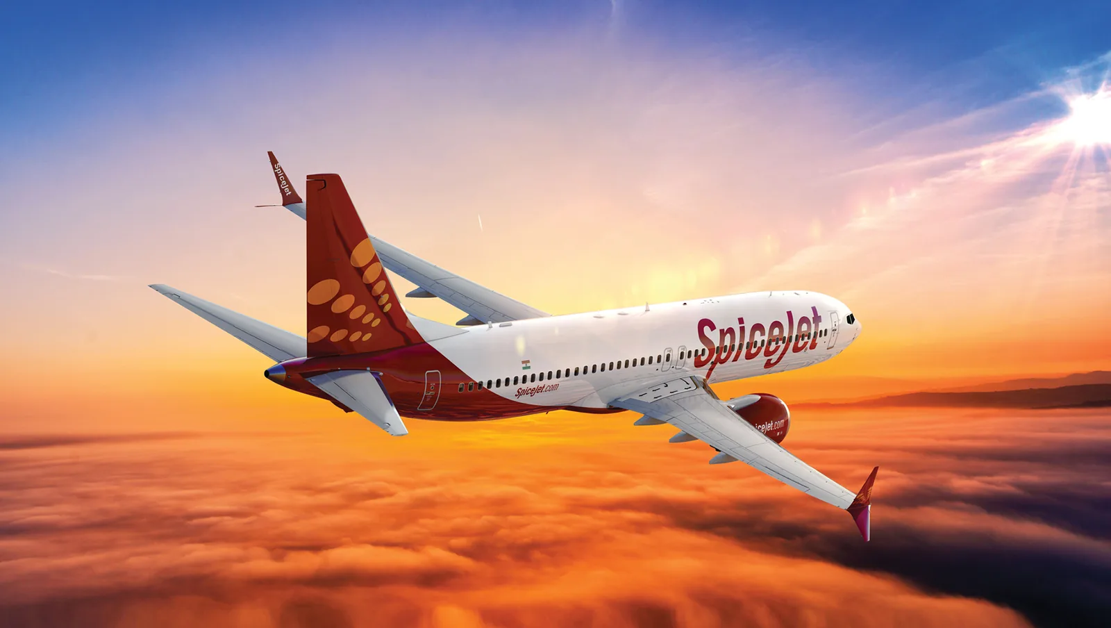 A SpiceJet Boeing 737 flying above the clouds at sunset