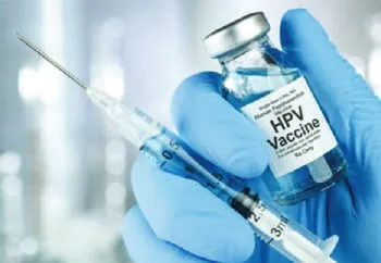 A gloved hand holding an HPV vaccine vial and syringe