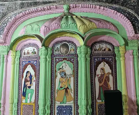 A painted fresco of figures inside carved green arches