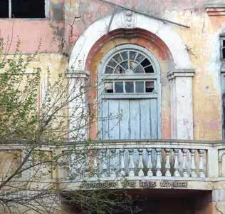 An old building with an arched window and a carved balcony