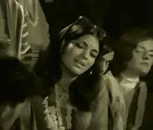 A black-and-white film still of women singing