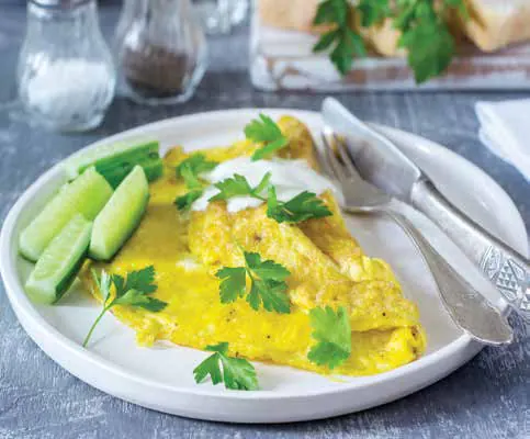 A masala omelette with cucumber and herbs on a plate