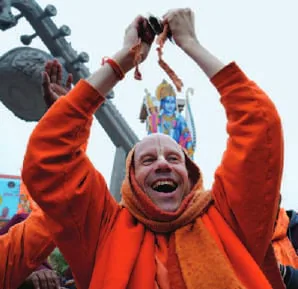 A devotee in saffron raising his arms
