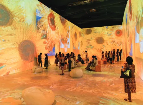 Visitors in an immersive gallery with Van Gogh paintings projected on the walls
