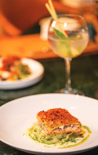A cocktail and a plated dish on a restaurant table