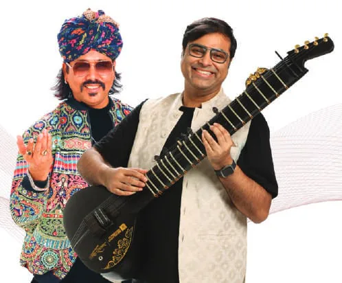 A folk musician in a turban beside a man holding an electric guitar
