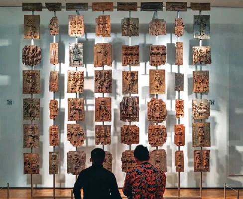 Visitors looking at a wall of artefacts in a museum