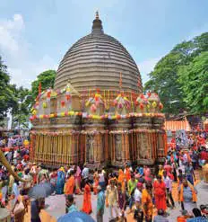 Crowds of pilgrims around a domed temple decorated with flowers