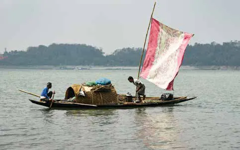 A wooden boat with a patched sail on a wide river