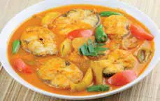 A fish curry with tomatoes in a white bowl