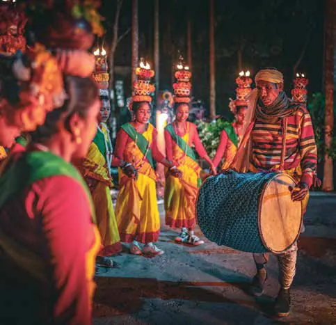 Performers in bright costumes dancing with drums at night