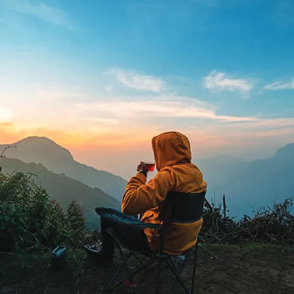 A traveller in a hooded jacket looking out over misty hills