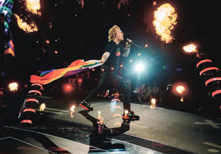 Ed Sheeran performing on stage with flames behind him