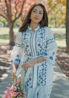 A woman in a white dress with blue embroidery, holding flowers