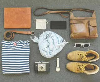 A flat lay of travel essentials: a striped T-shirt, a camera, boots, sunglasses and a leather bag