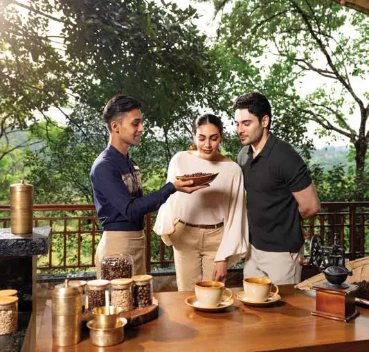 A man serving coffee to two guests at an outdoor table