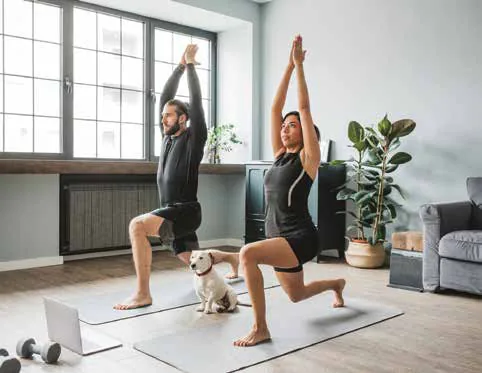 A man and a woman doing yoga lunges with a small dog between them