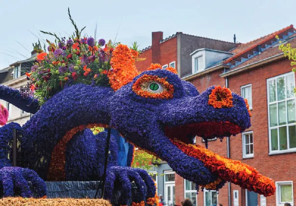 A parade float shaped like a dragon covered in flowers