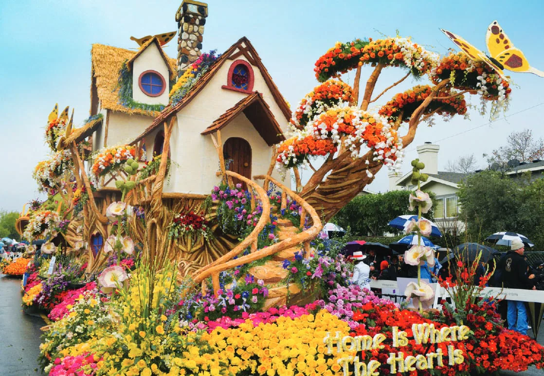 A parade float decorated with flowers and a house