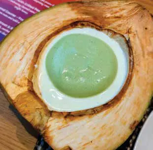 A green drink served in a halved coconut