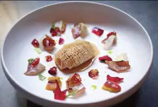 A white bowl with a small plated dish and scattered garnish