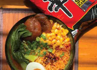 A bowl of ramen with corn, greens and an egg