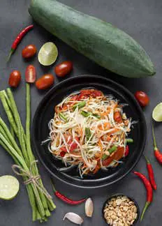 A plate of som tam with fresh vegetables and chillies