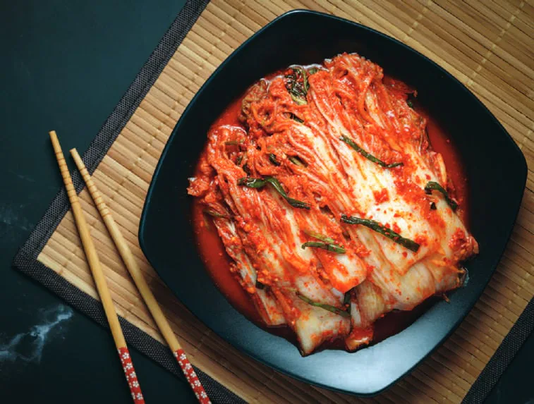 Kimchi in a black bowl with chopsticks