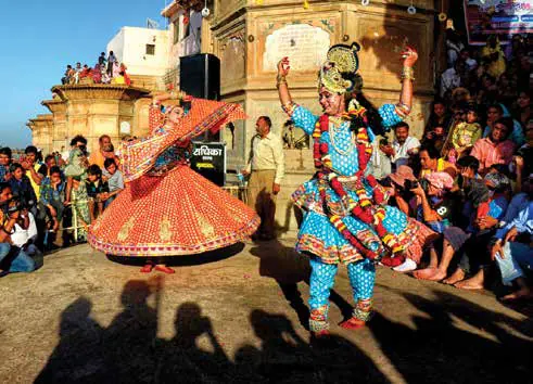 A performer in a swirling orange skirt dancing before a crowd
