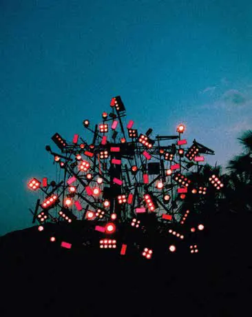 A sculpture of red lights against a night sky