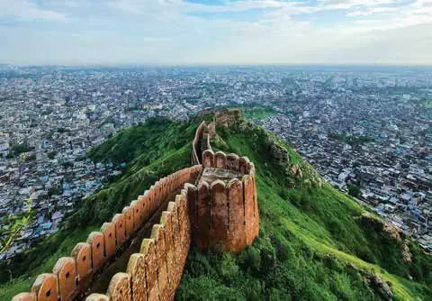 A fort wall winding along a green ridge above the city