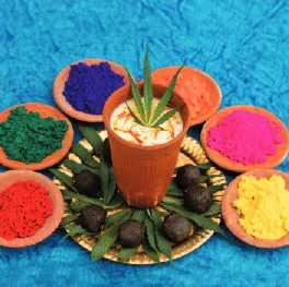 A glass of a Holi drink among bowls of coloured powder