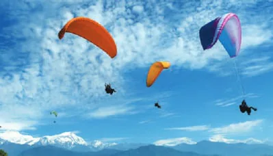 Paragliders over a green valley