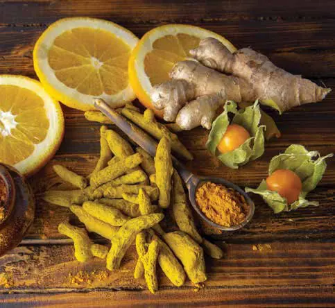 Fresh turmeric, ginger and lemon slices on a wooden board