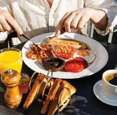 A plated breakfast of eggs, sausages, toast and orange juice