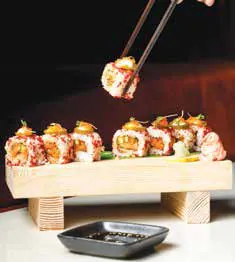Sushi pieces lifted with chopsticks from a wooden stand