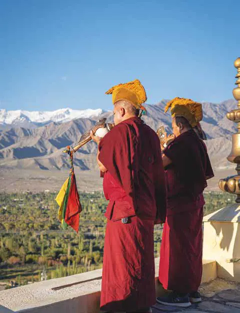 Two monks in red robes blowing long horns