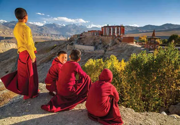 Young monks in red robes resting on a hillside