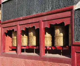 A row of prayer wheels set in a red wall