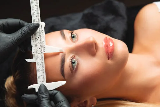 A technician working on a woman’s brows
