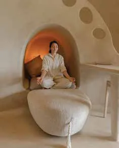 A woman meditating in a curved, cave-like alcove