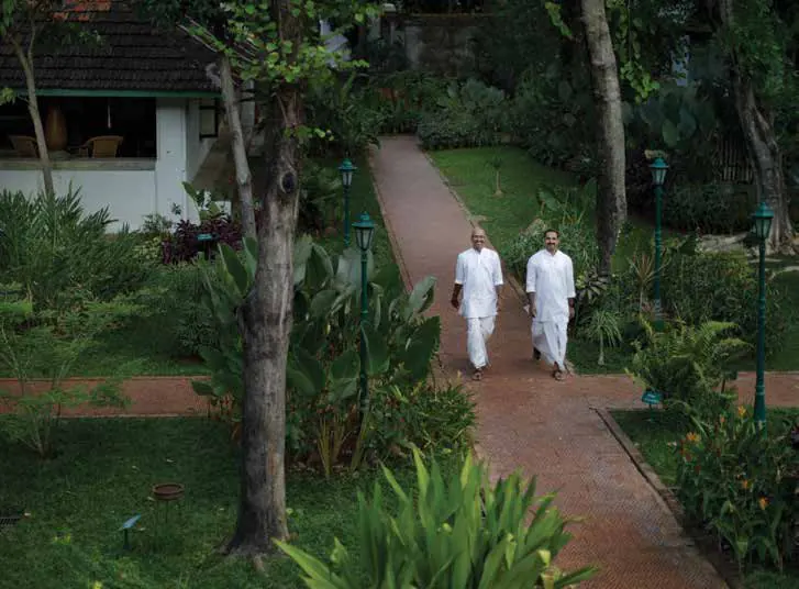 Two people in white walking along a garden path