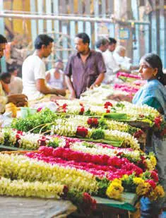 Flower sellers stringing garlands at a market stall