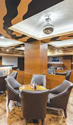 Tables and chairs in a restaurant under a patterned ceiling