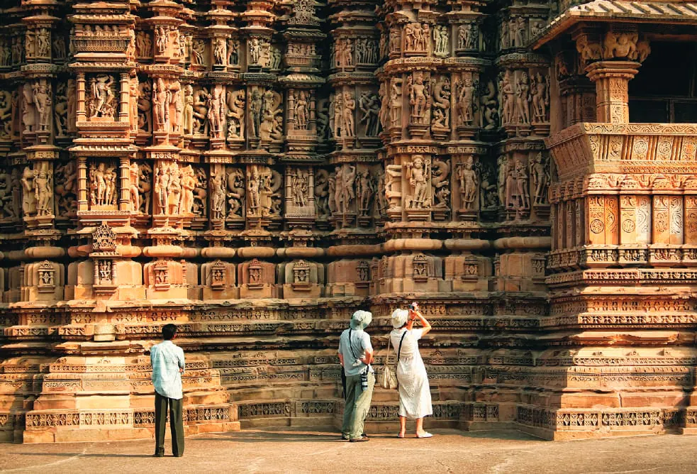 Visitors photographing the carved walls of a Khajuraho temple