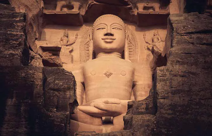 A large seated statue carved into a rock face