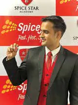 Portrait of a man in a black suit and red tie in front of a SpiceJet banner
