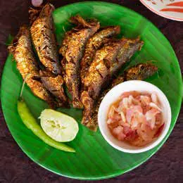 Fried fish served on a banana leaf with lime and a dip