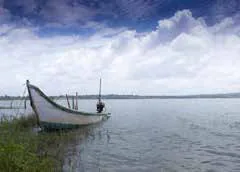 A small boat on a calm lake under a cloudy sky