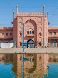 A pink mosque gateway reflected in water